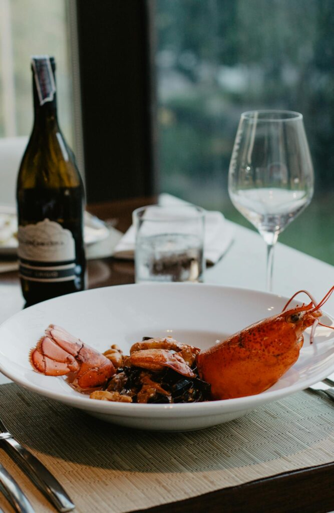 Delicious freshly boiled lobster with spices on white ceramic plate served with aromatic wine in fine dine restaurant